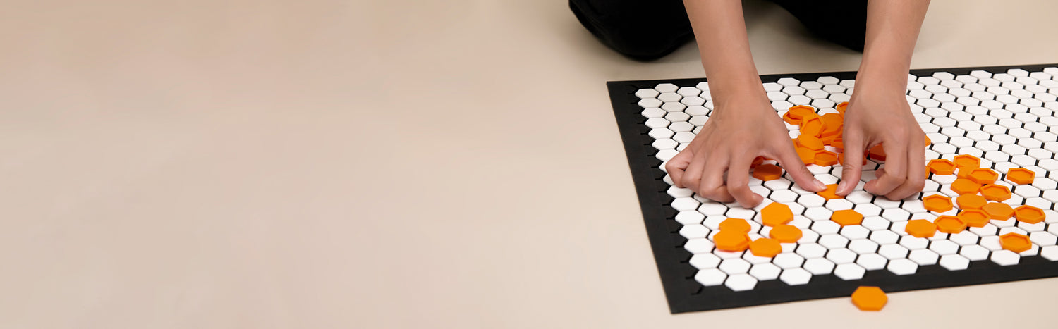 Hand adding tiles to the Letterfolk Tile mat.
