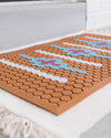 A close up of the Letterfolk Clay Tile Mat on a door step.