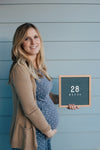 A pregnant Lady holding the Letterfolk Grey Poet Letter Board on a blue background. 