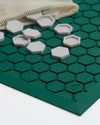A close up image of the Letterfolk Standard Green Tile Mat with tiles spilling out of a mesh pouch. 