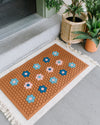 The Letterfolk Clay Tile Mat displayed on a front porch. 
