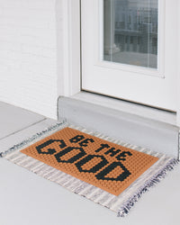 The Letterfolk "BE THE GOOD" Clay Tile Mat on a doorstep. 