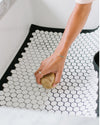 An image of a hand cleaning the Letterfolk White Tile Mat. 