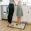 A woman and child standing on a Letterfolk tile mat in the Kitchen. 
